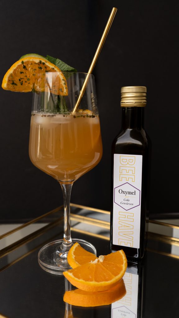 Oxymel mit Cola-Gewuerzen im Glas mit Orangenscheiben